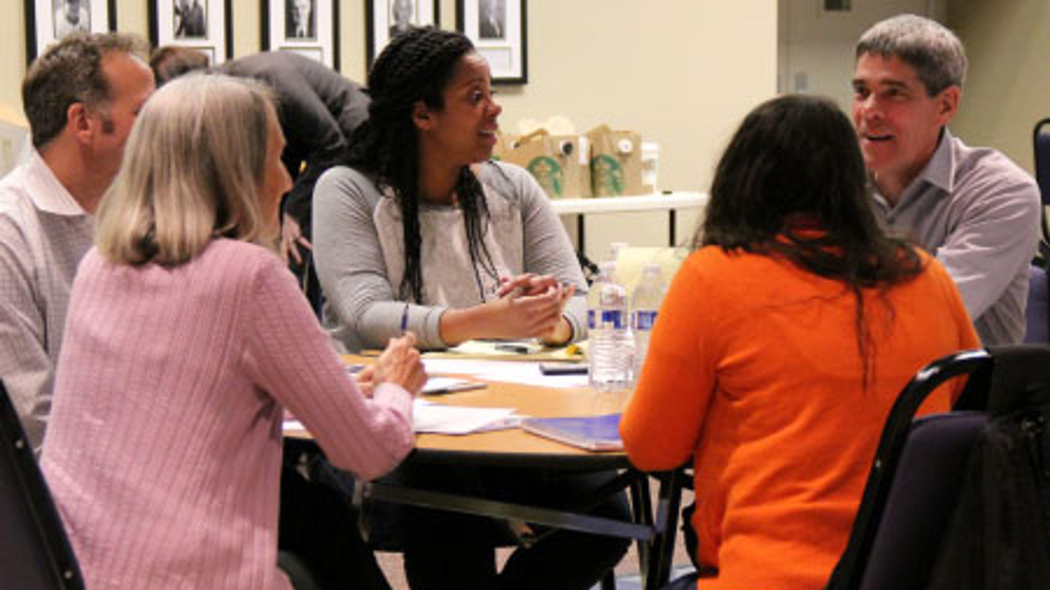 A diverse group of people sitting around a table at a housing forum in Vancouver, Washington