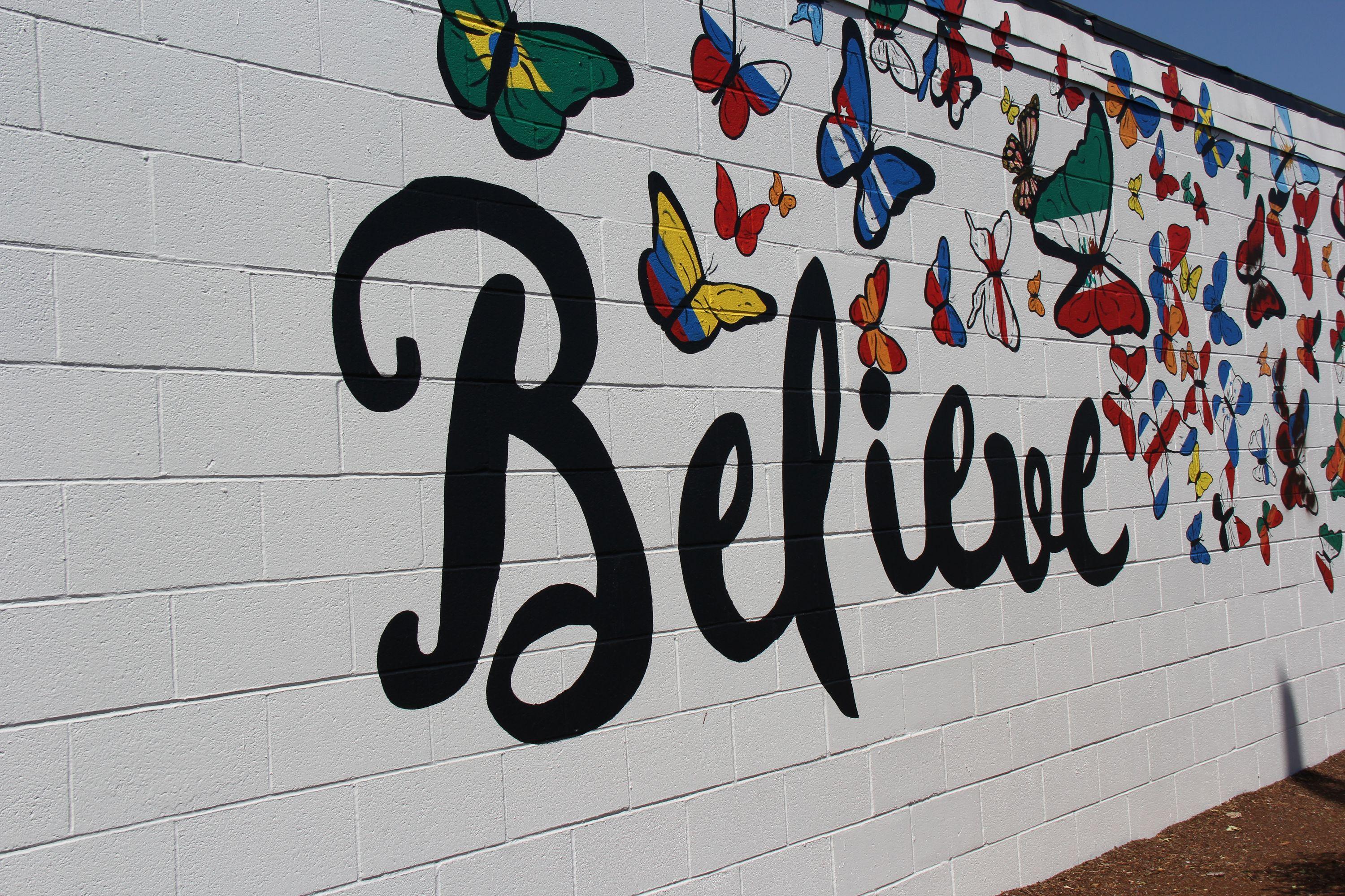 Believe mural with butterflies with wings featuring different flags painted on Fourth Plain Blvd