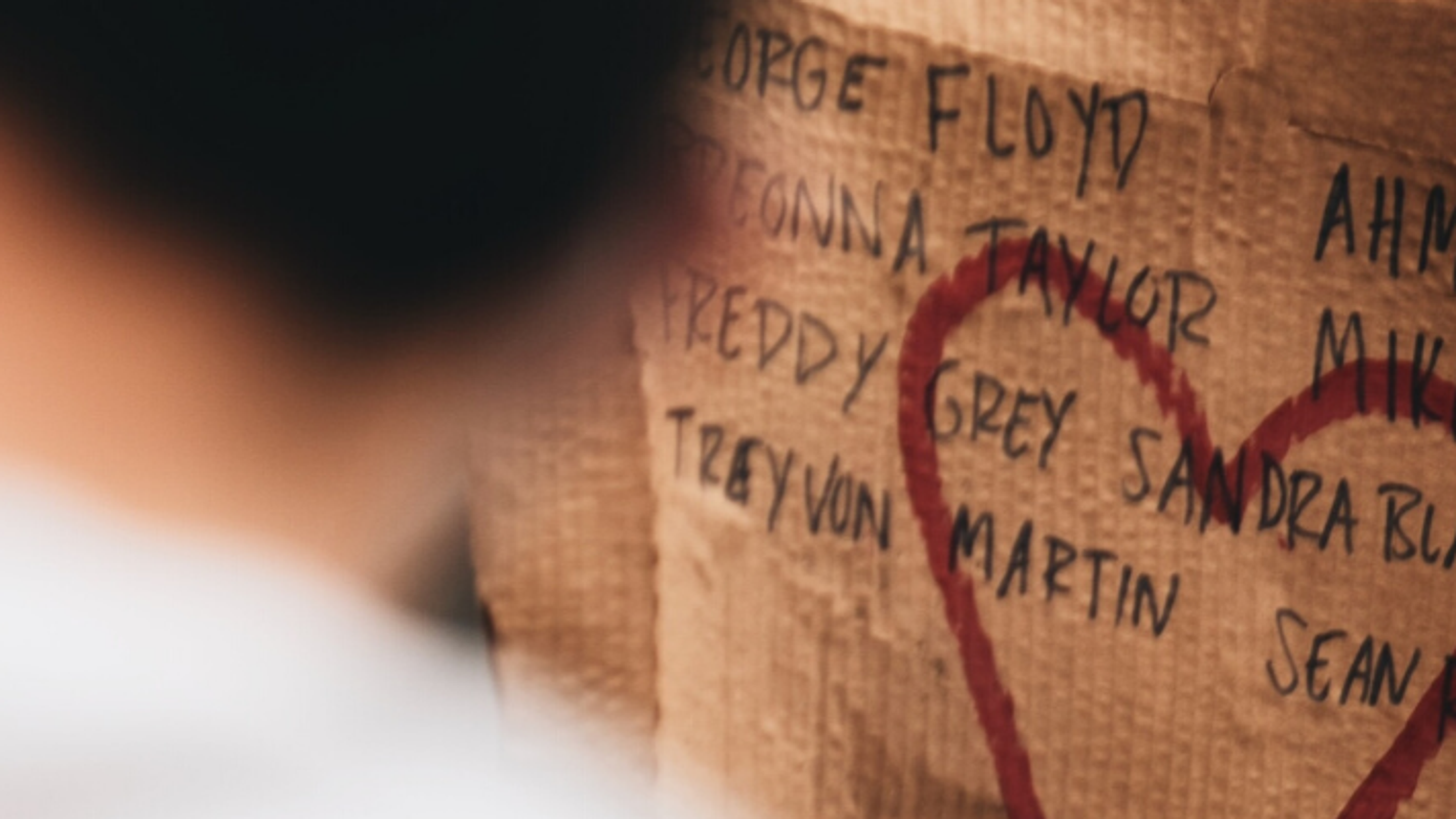 Heart drawn on cardboard listing the names of Black people killed in the USA: George Floyd, Breonna Taylor, Tony McDade, Rayshard Brooks and Ahmaud Arbery