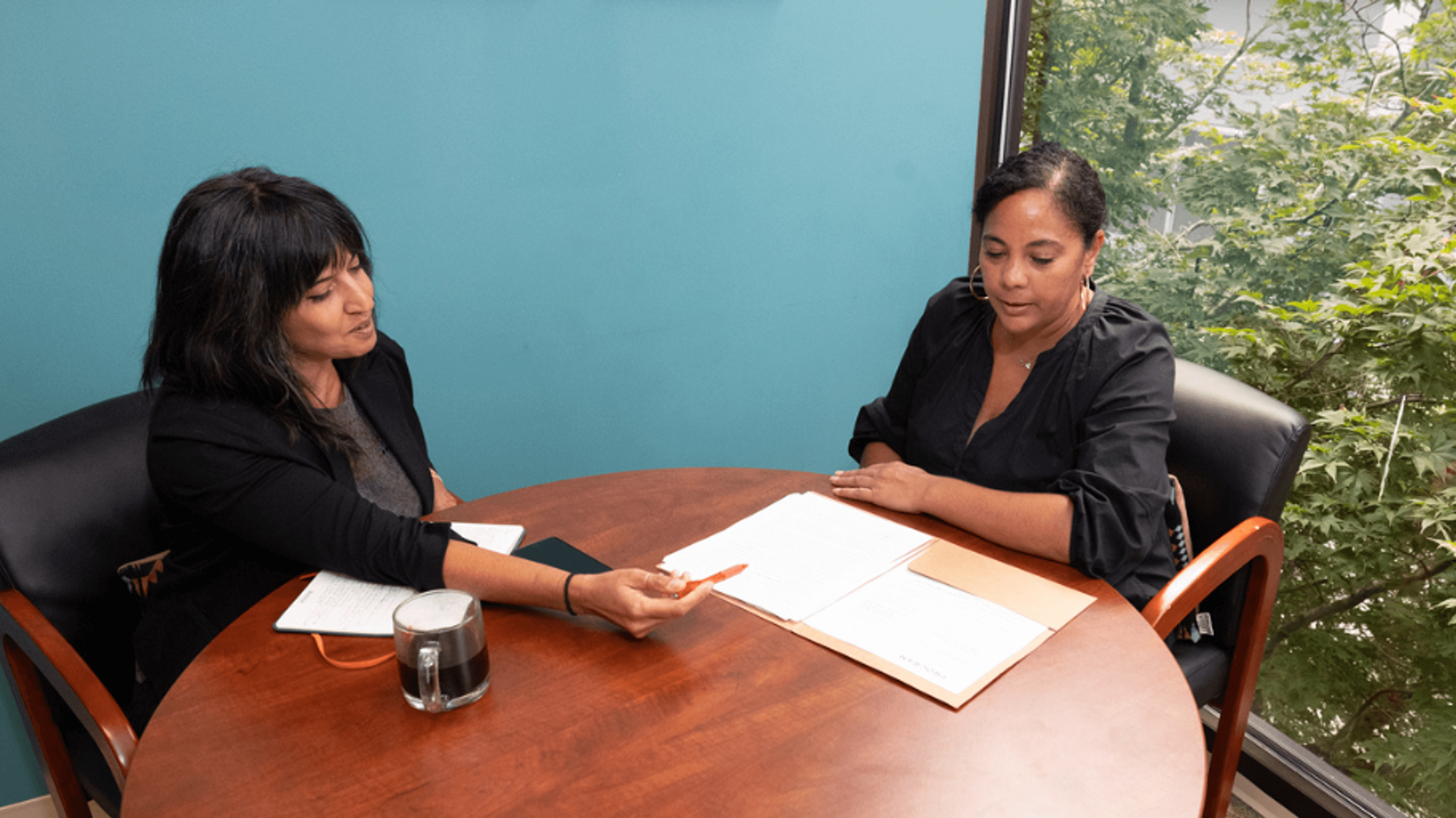 Esra and Ursula, an Indian woman and a Black woman, sitting together at a table reviewing notes together