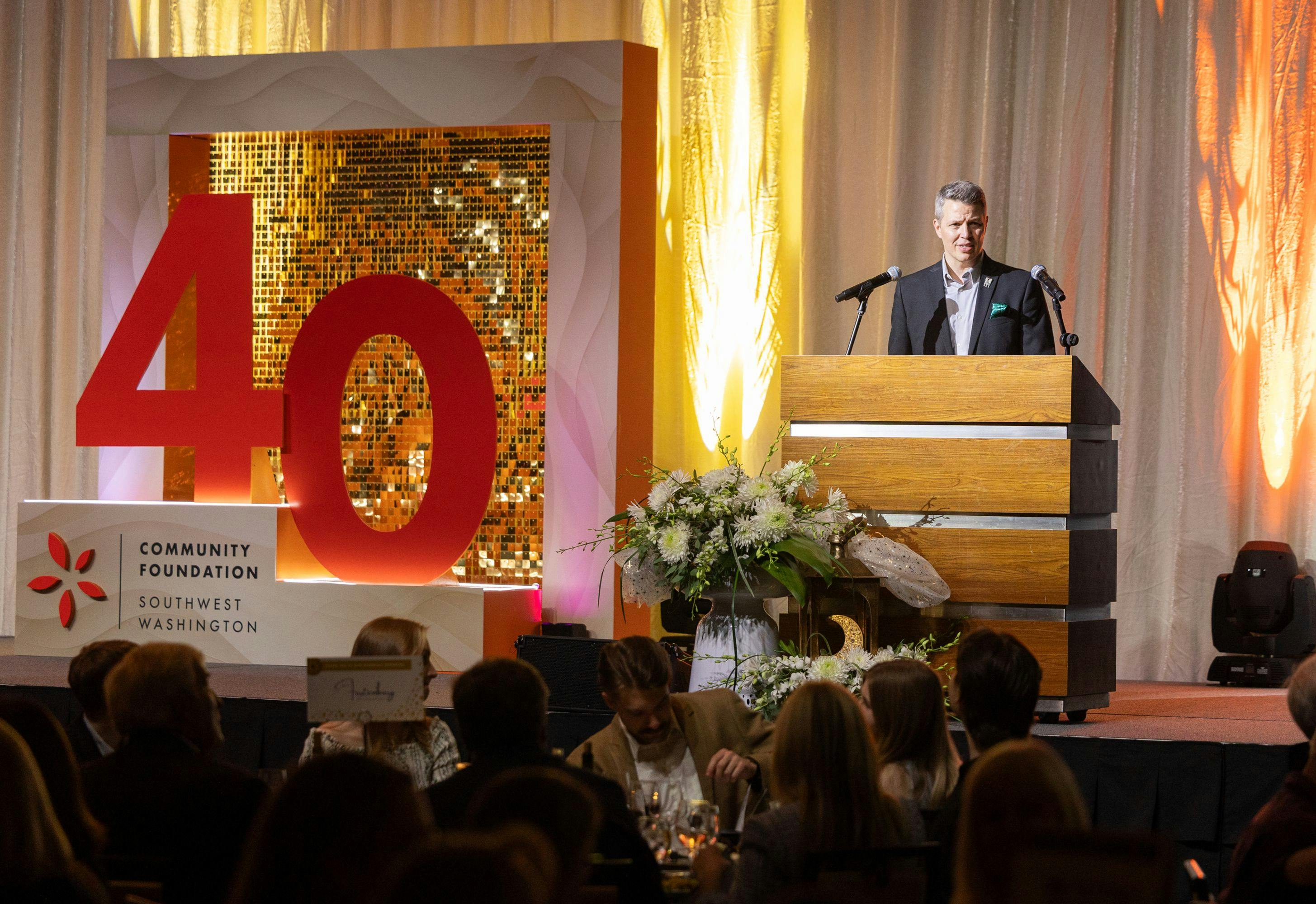 Matt Morton at the podium at ilani next to the 40th Anniversary stage decoration by BalloonGam