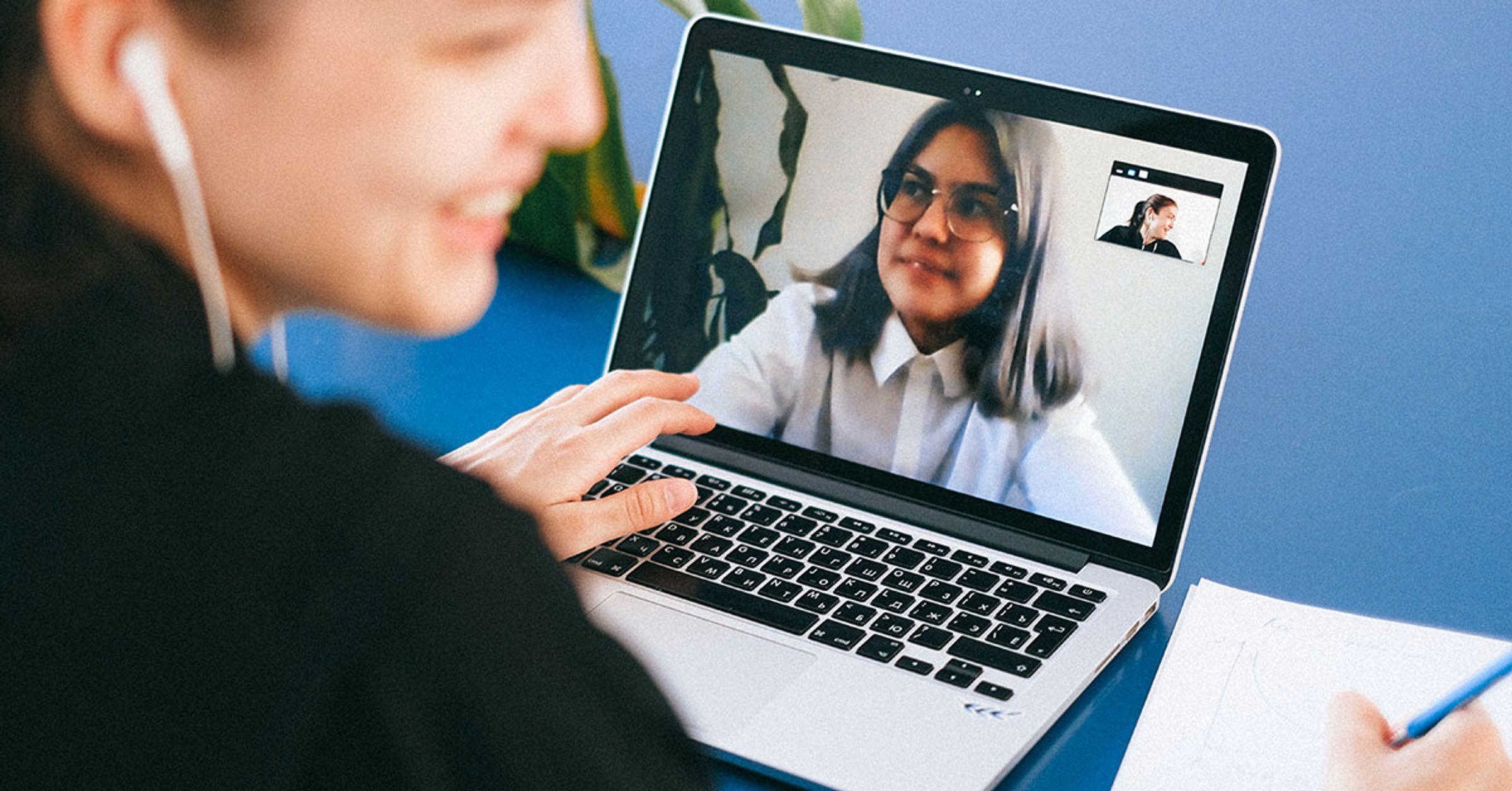 A person laughing while on a Zoom call on their laptop with another person