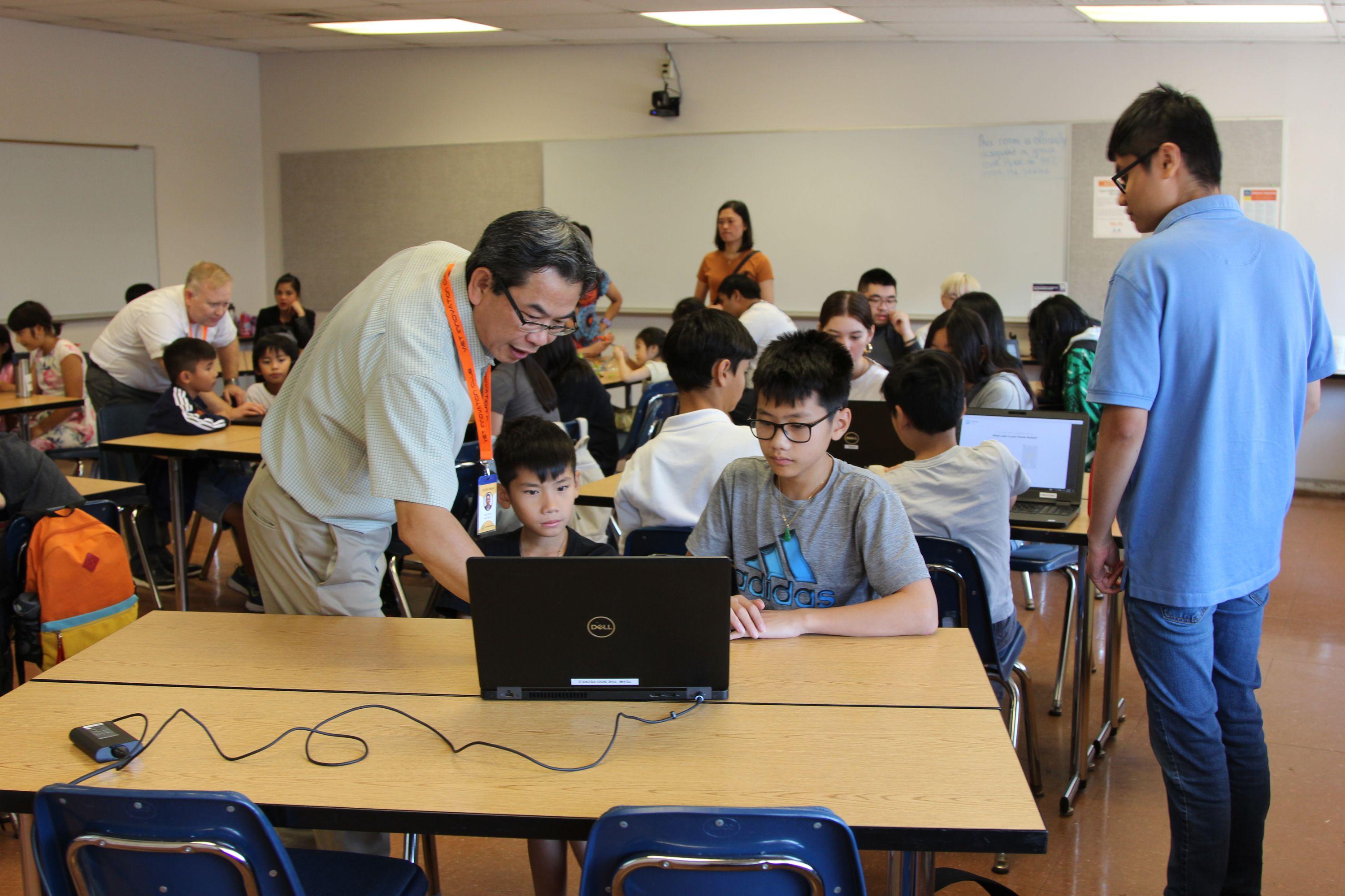 Two young boys learn from an adult at the Vietnamese Community of Clark County's Viet Innovation Club