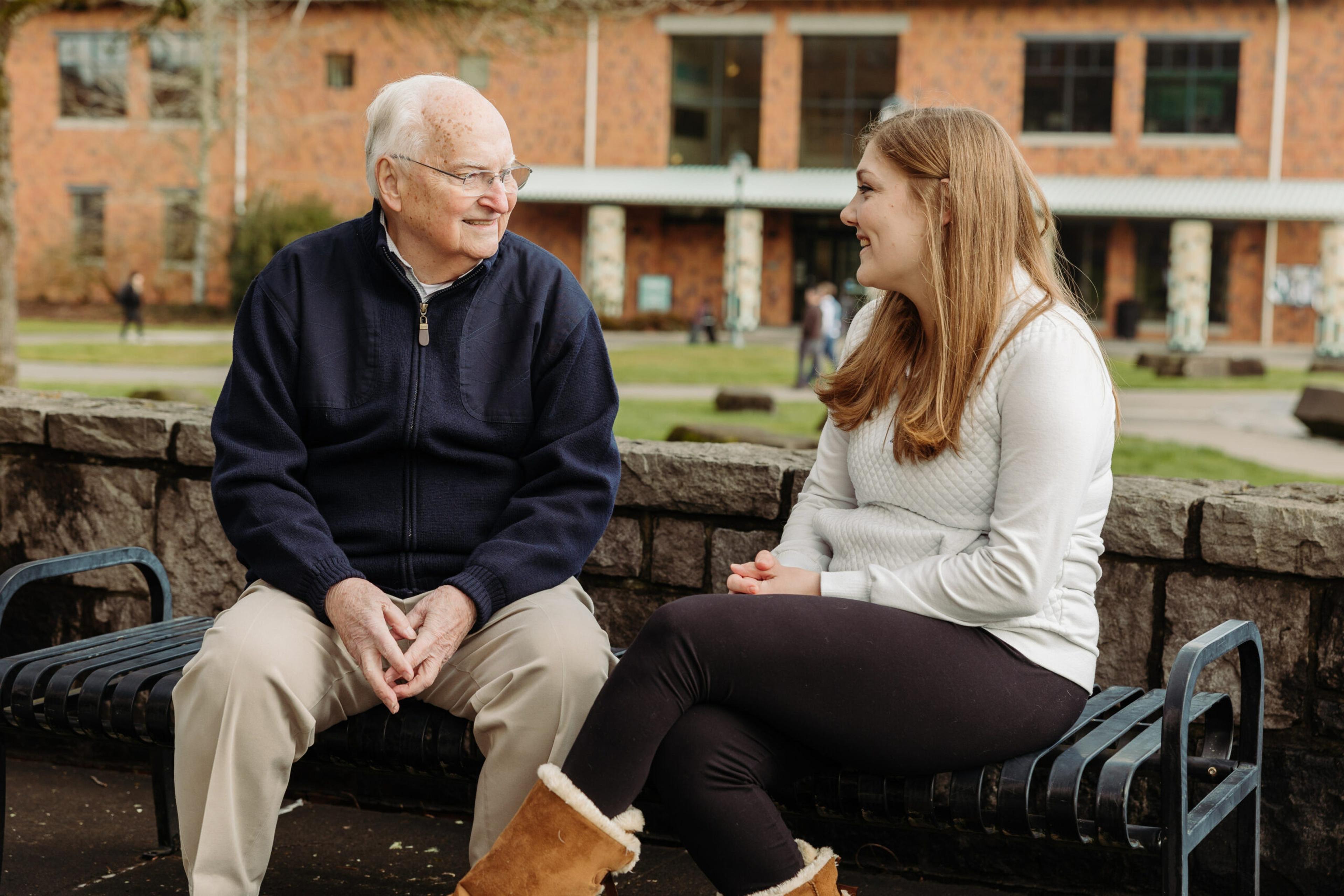 Ken Kirn and Sally Bovee sitting on a bench talking and smiling.