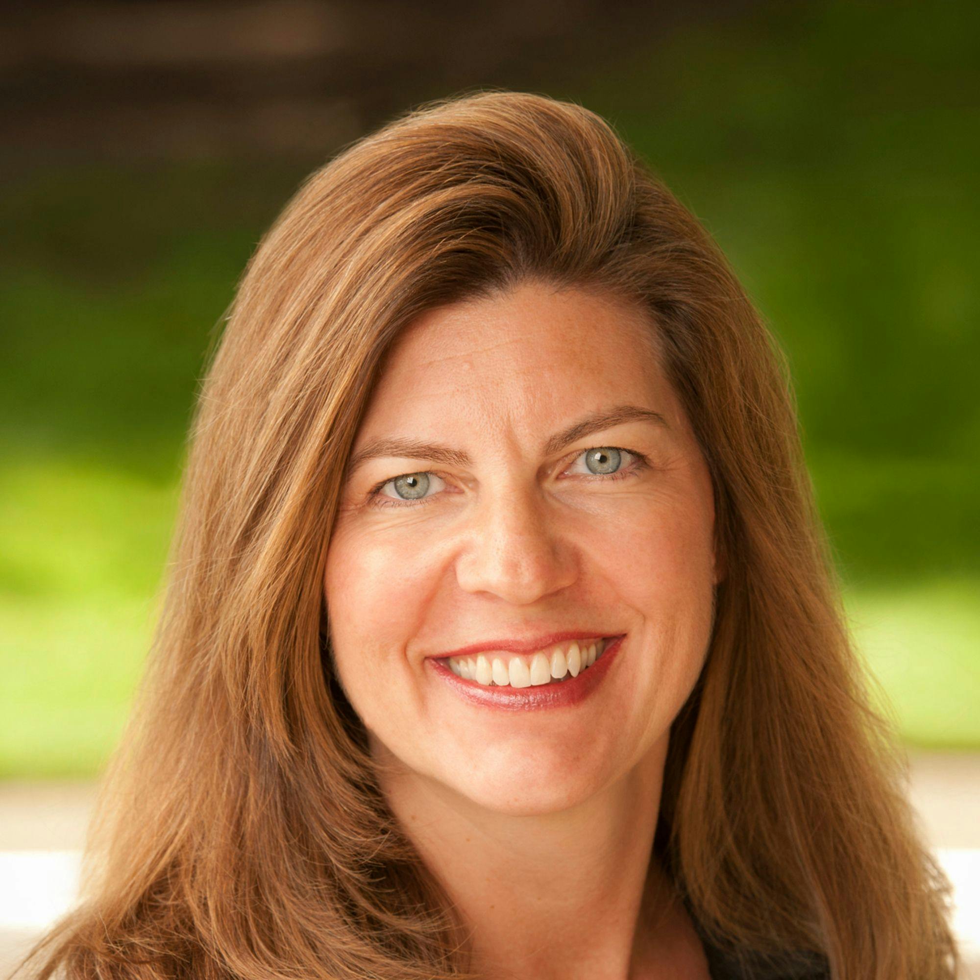 A red-haired woman smiling brightly at the camera