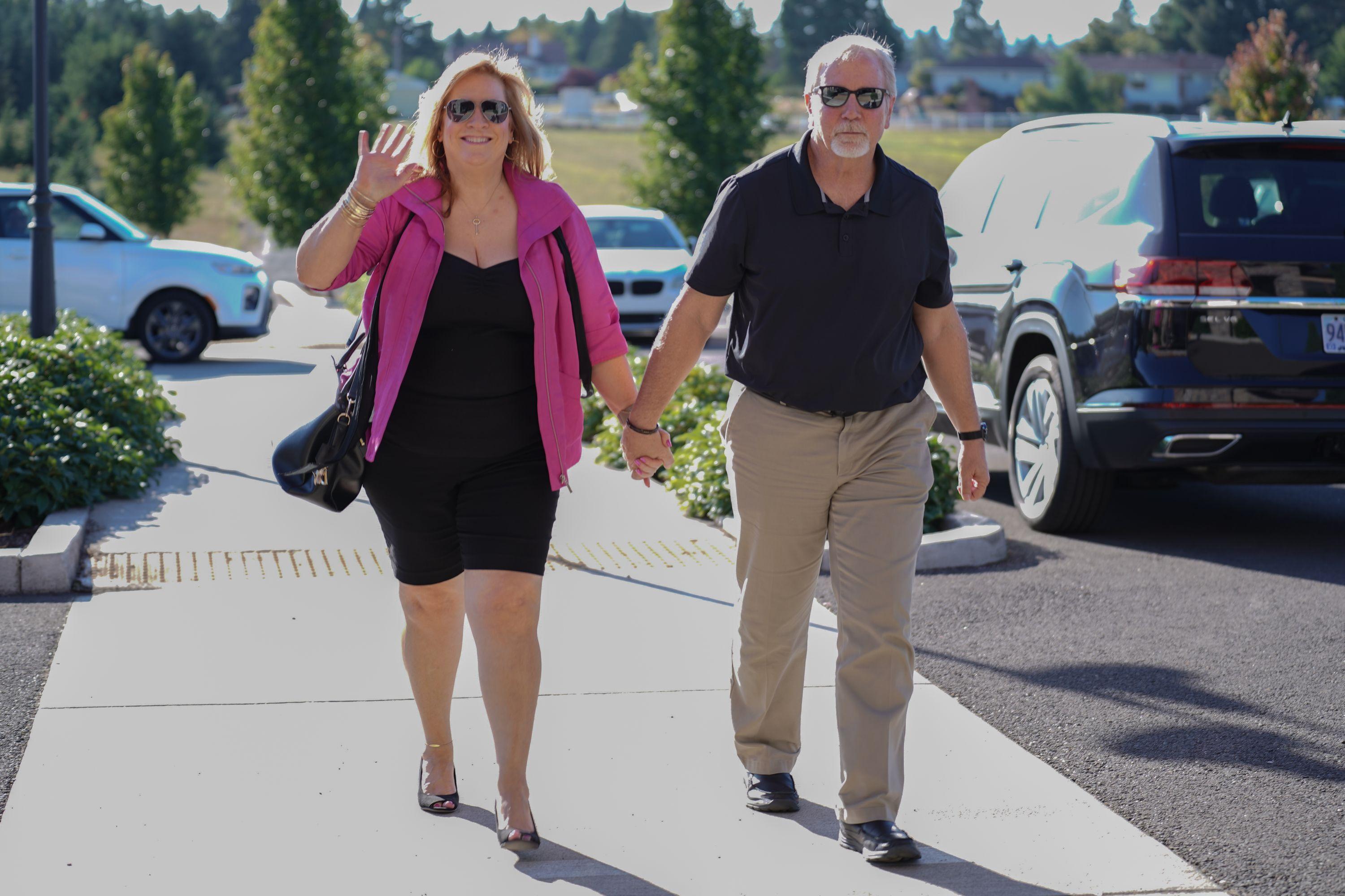 David Fuher of Realvest and his wife walking down the sidewalk smiling and waving