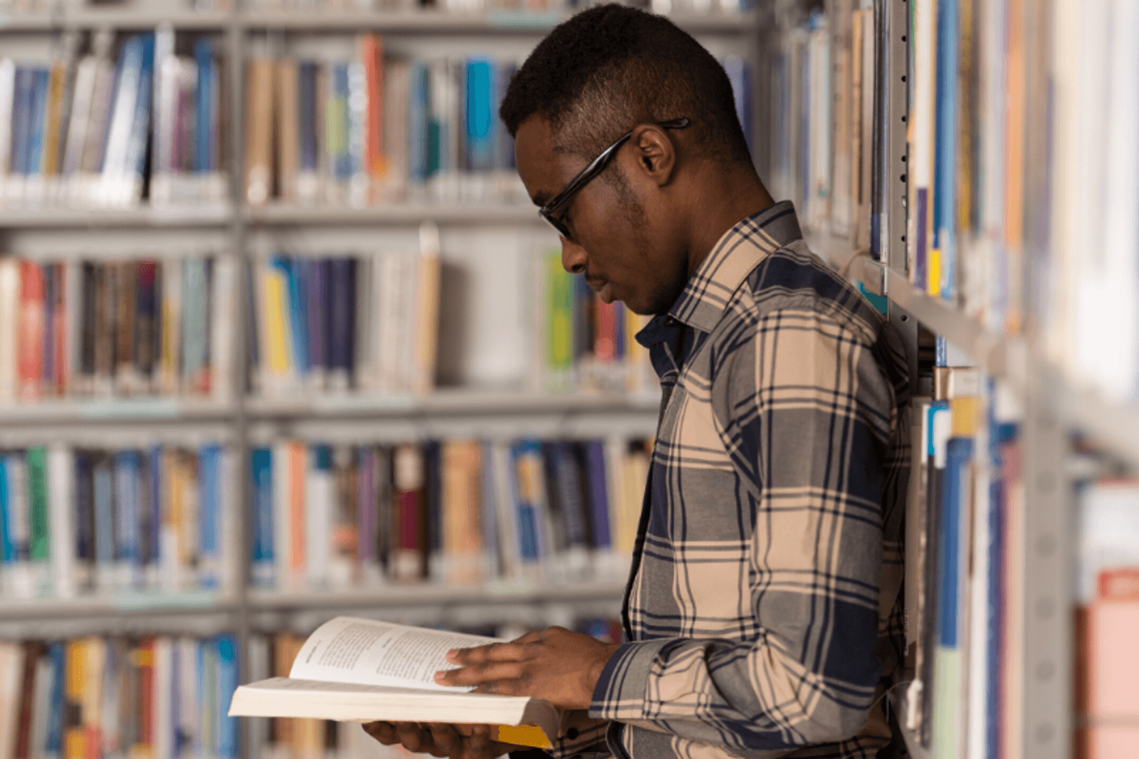 A Black student reading a book in a library