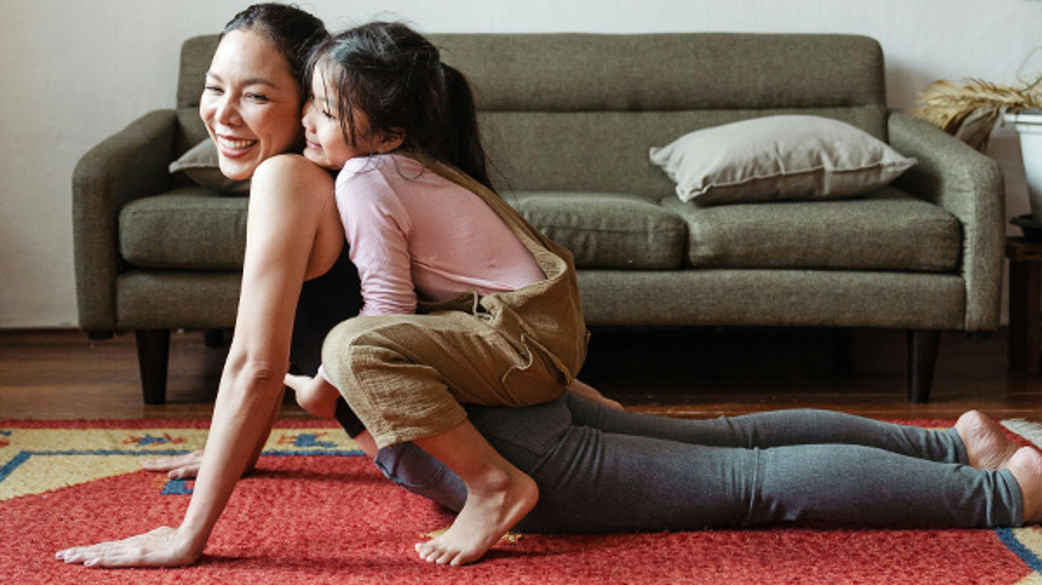 A woman stretching and laughing with her daughter