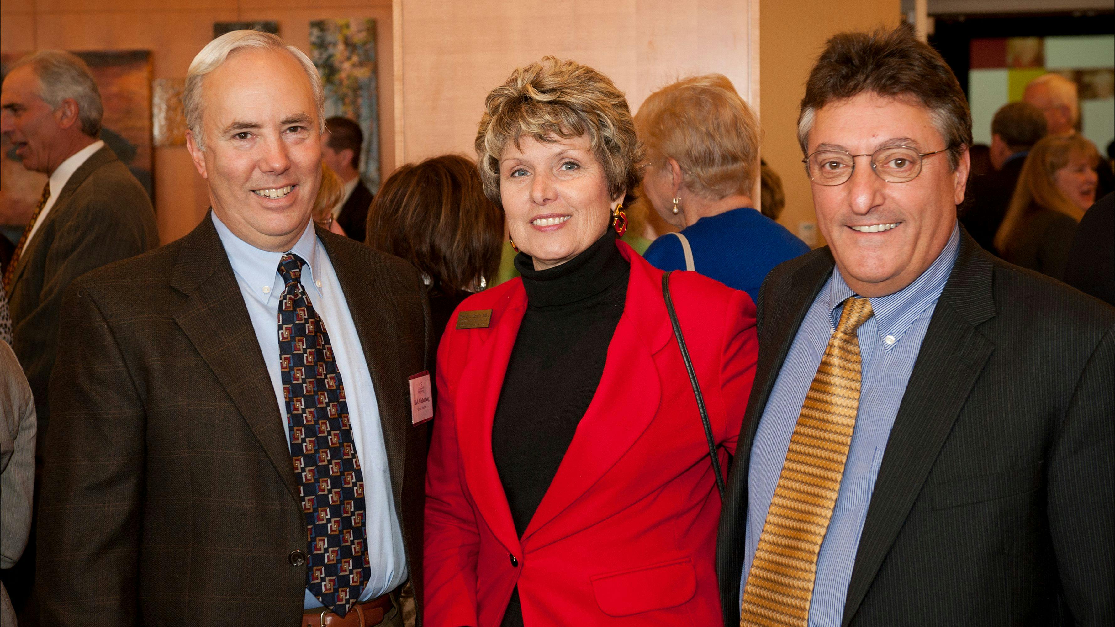 Rick Wollenberg, a white-haired man, next to a blonde woman and a dark-haired man at an Annual Celebration Event