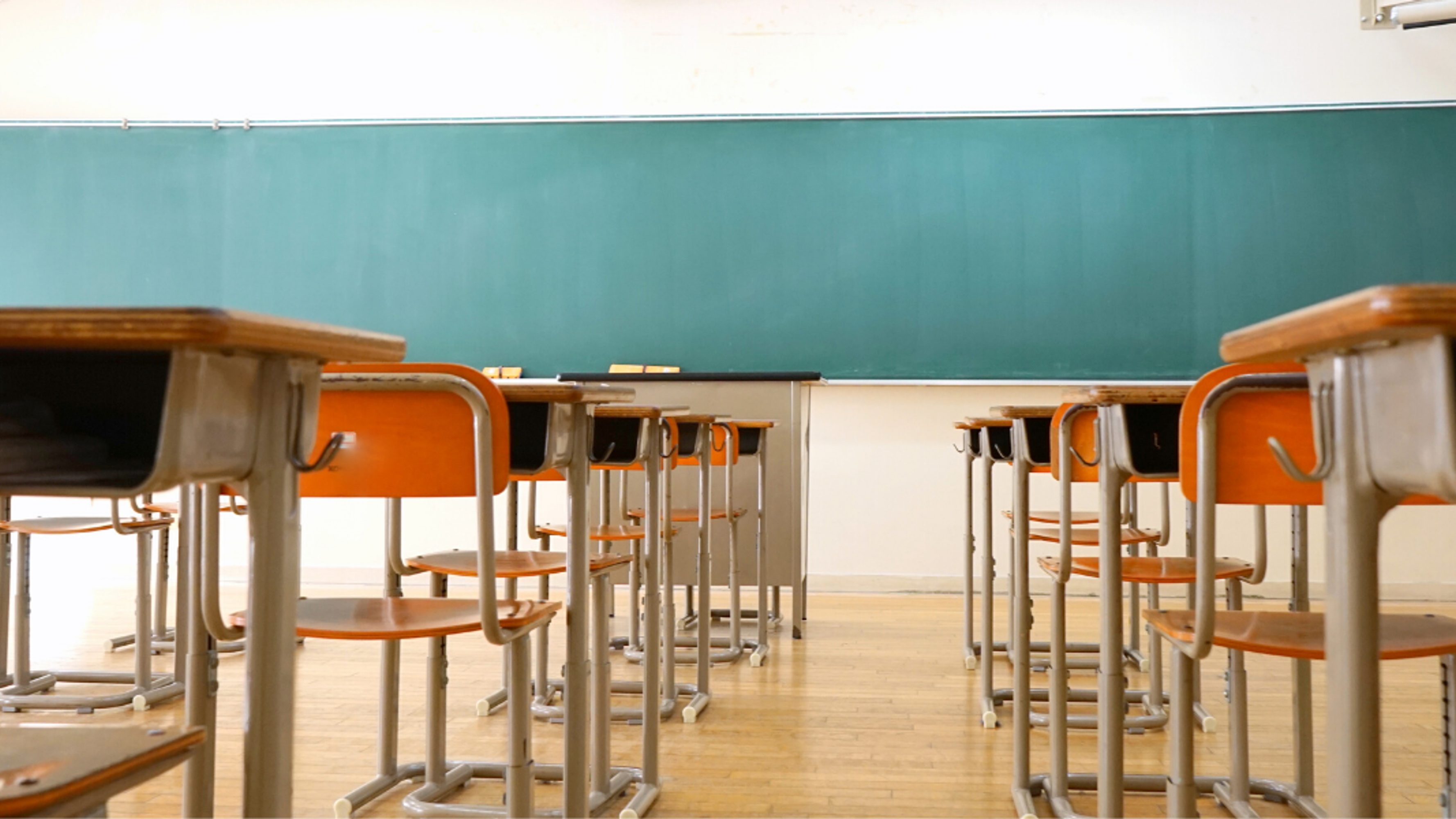 Empty classroom in a school with a chalkboard, chairs and desks