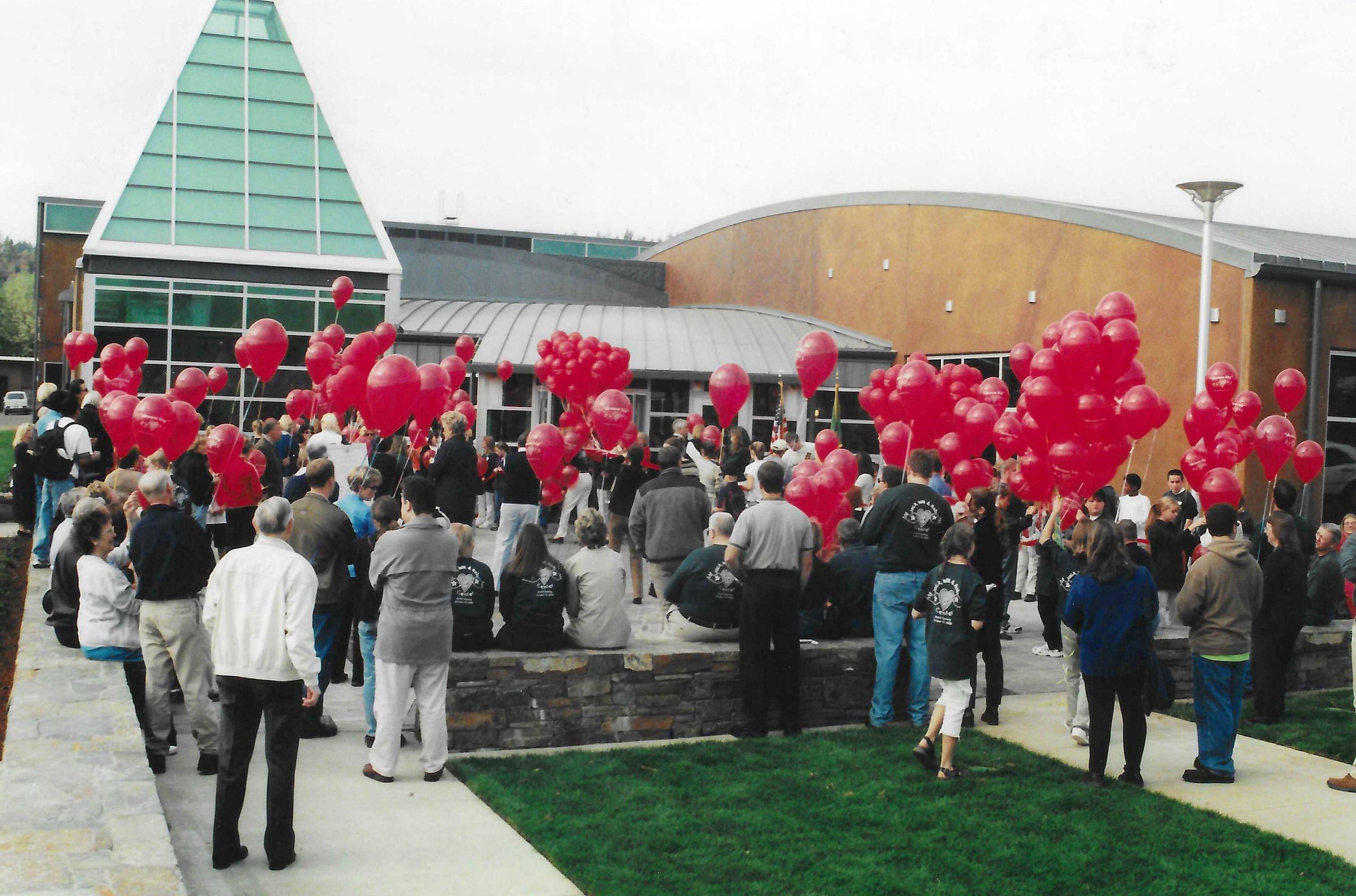 Community members gather and hold red balloons to celebrate the grand opening of the Jim Parsley Center. 