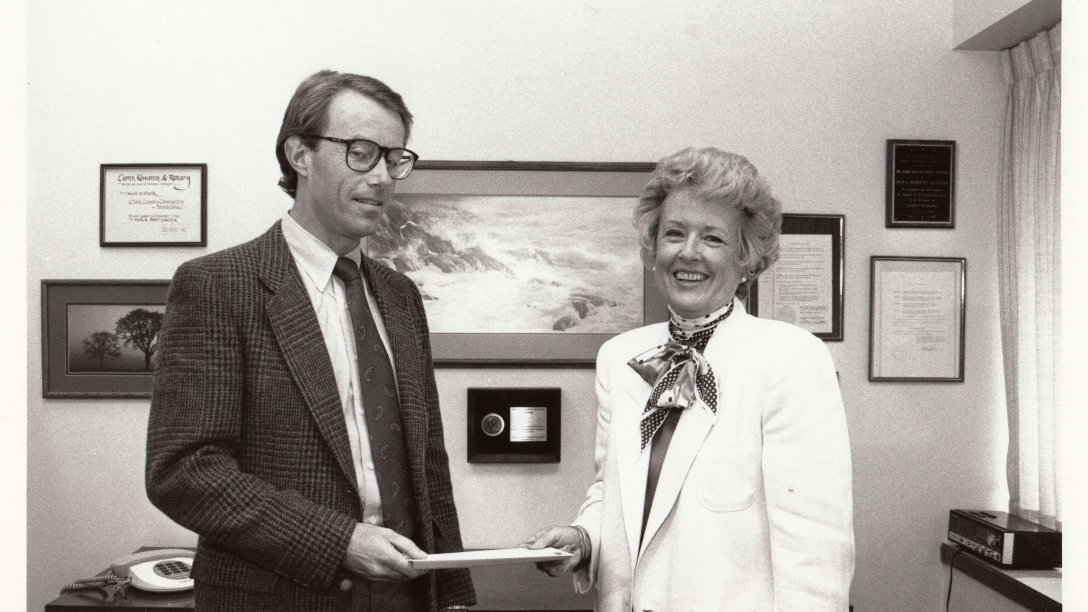 Mary Granger shaking hands with a tall man in a suit with glasses