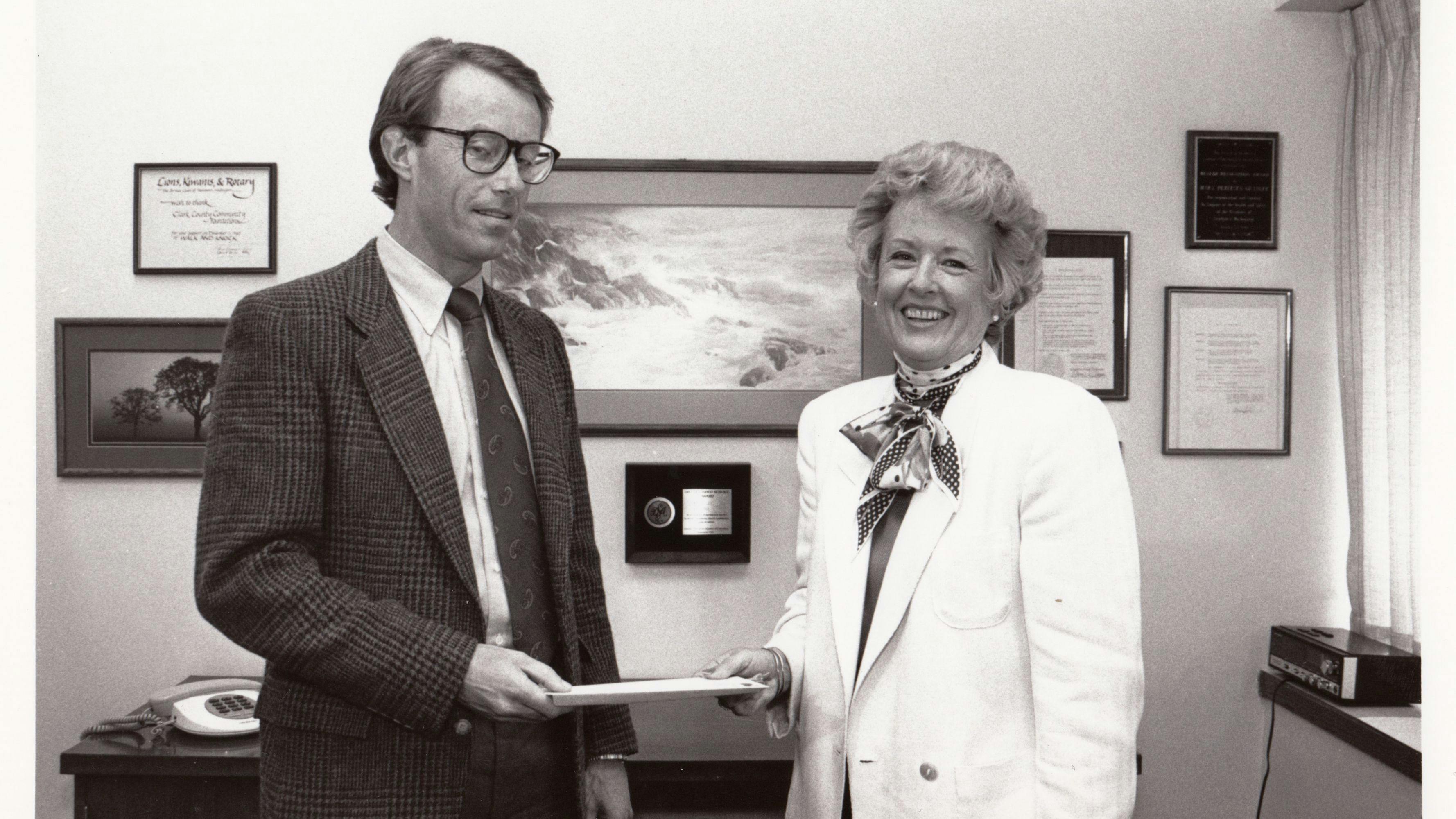 Mary Granger shaking hands with a tall man in a suit with glasses