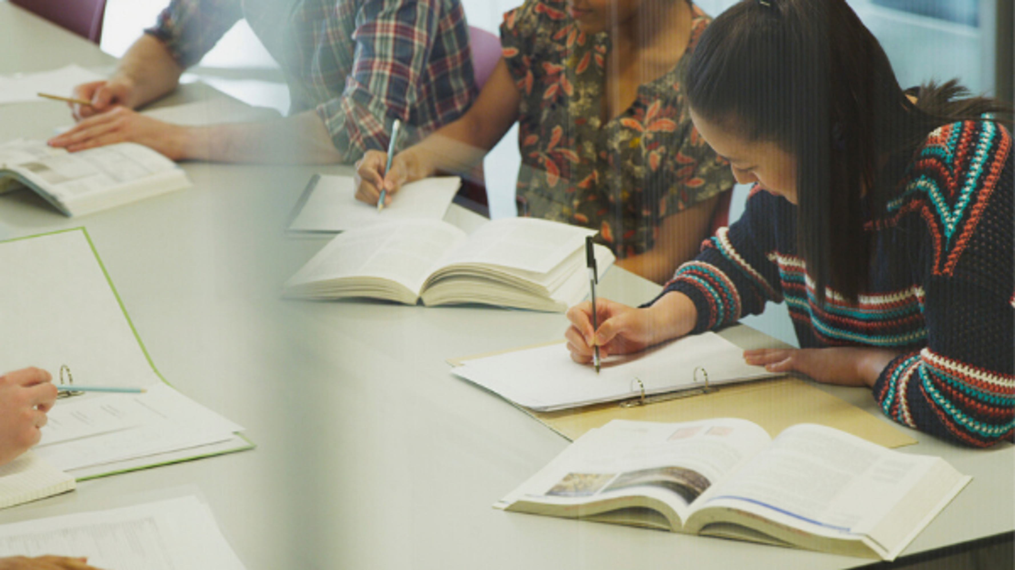 Diverse students around a table taking notes