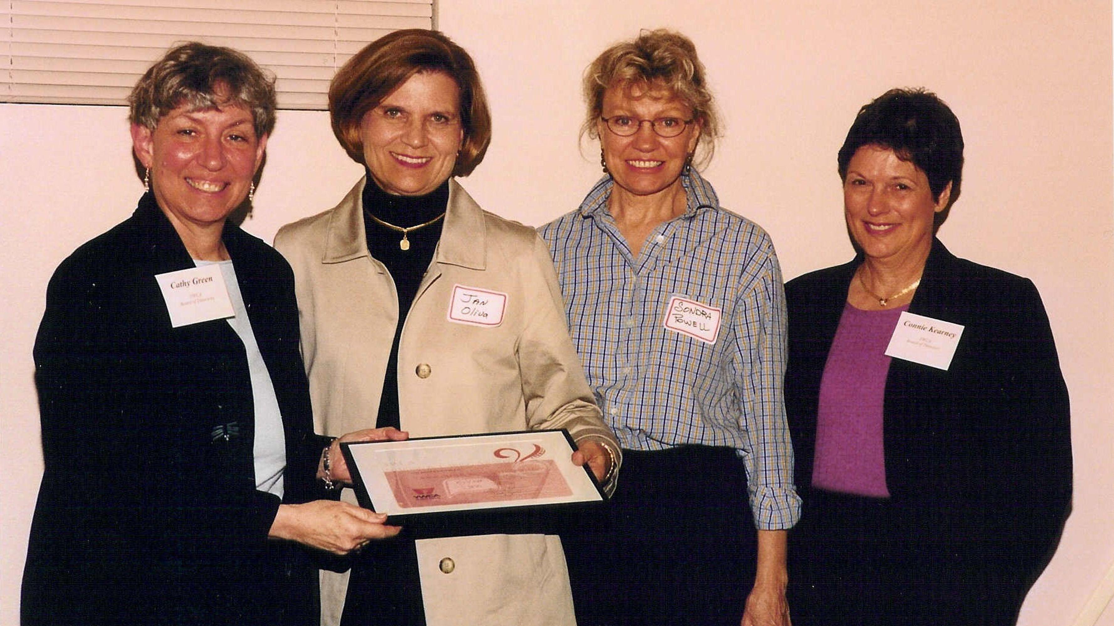 Four women holding a plaque and smiling at the camera