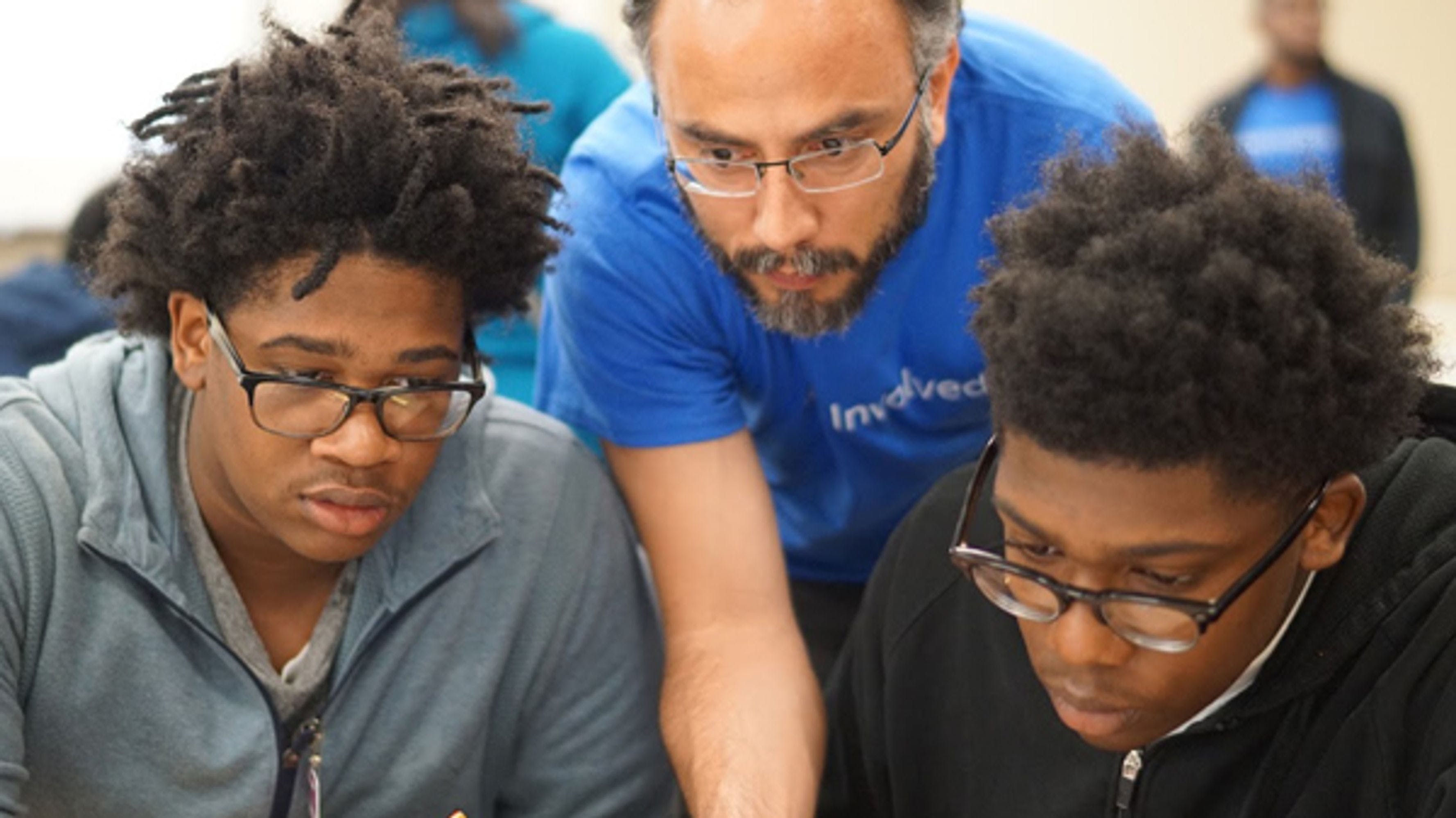 Two students of color and an adult looking at something together at iUrban Teen in Vancouver, Washington