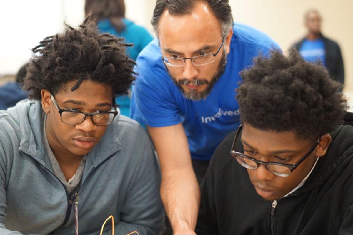 Two students of color and an adult looking at something together at iUrban Teen in Vancouver, Washington