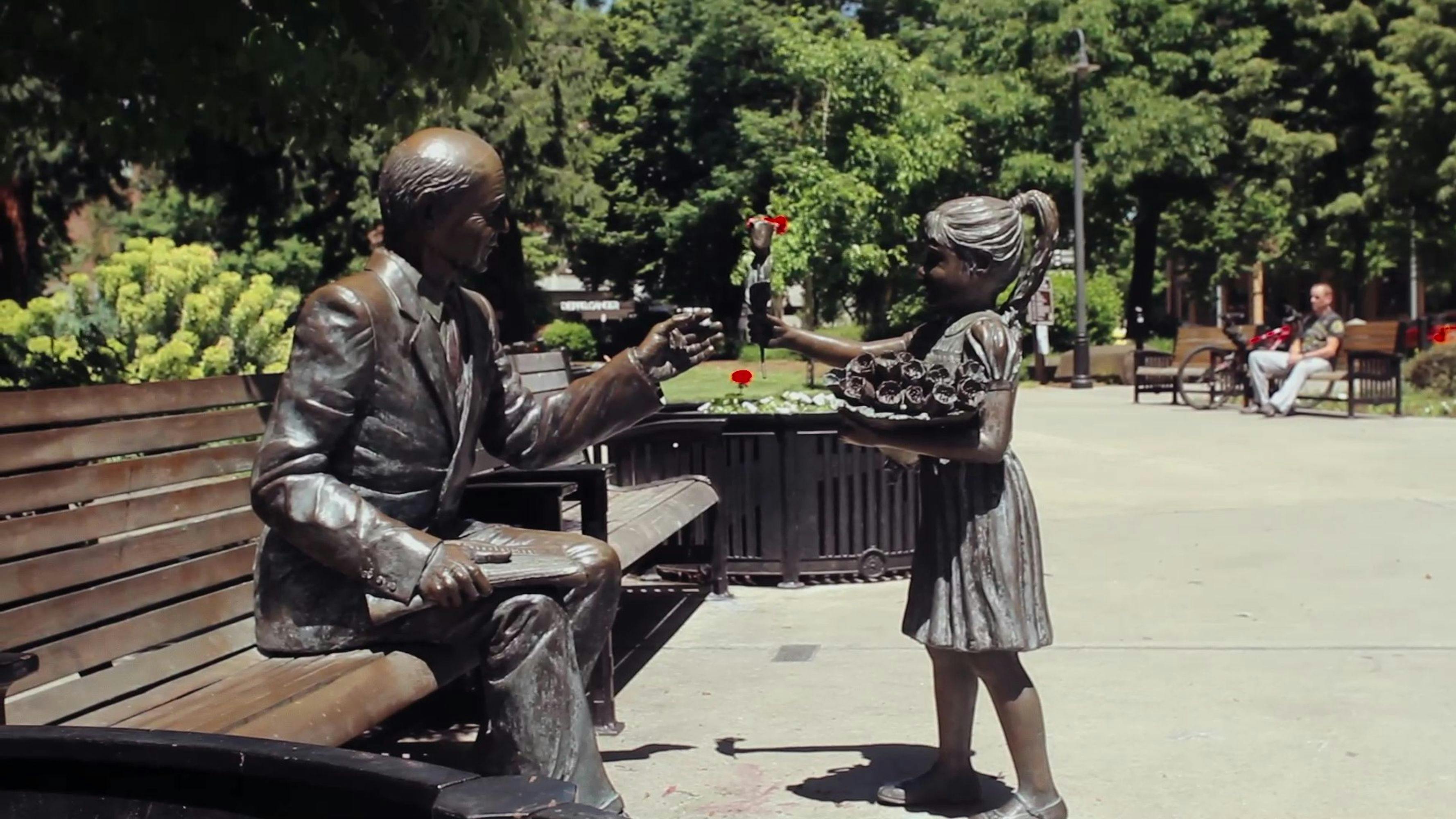 Statue in Esther Short Park in Vancouver, WA of young girl giving a flower to a man on a bench