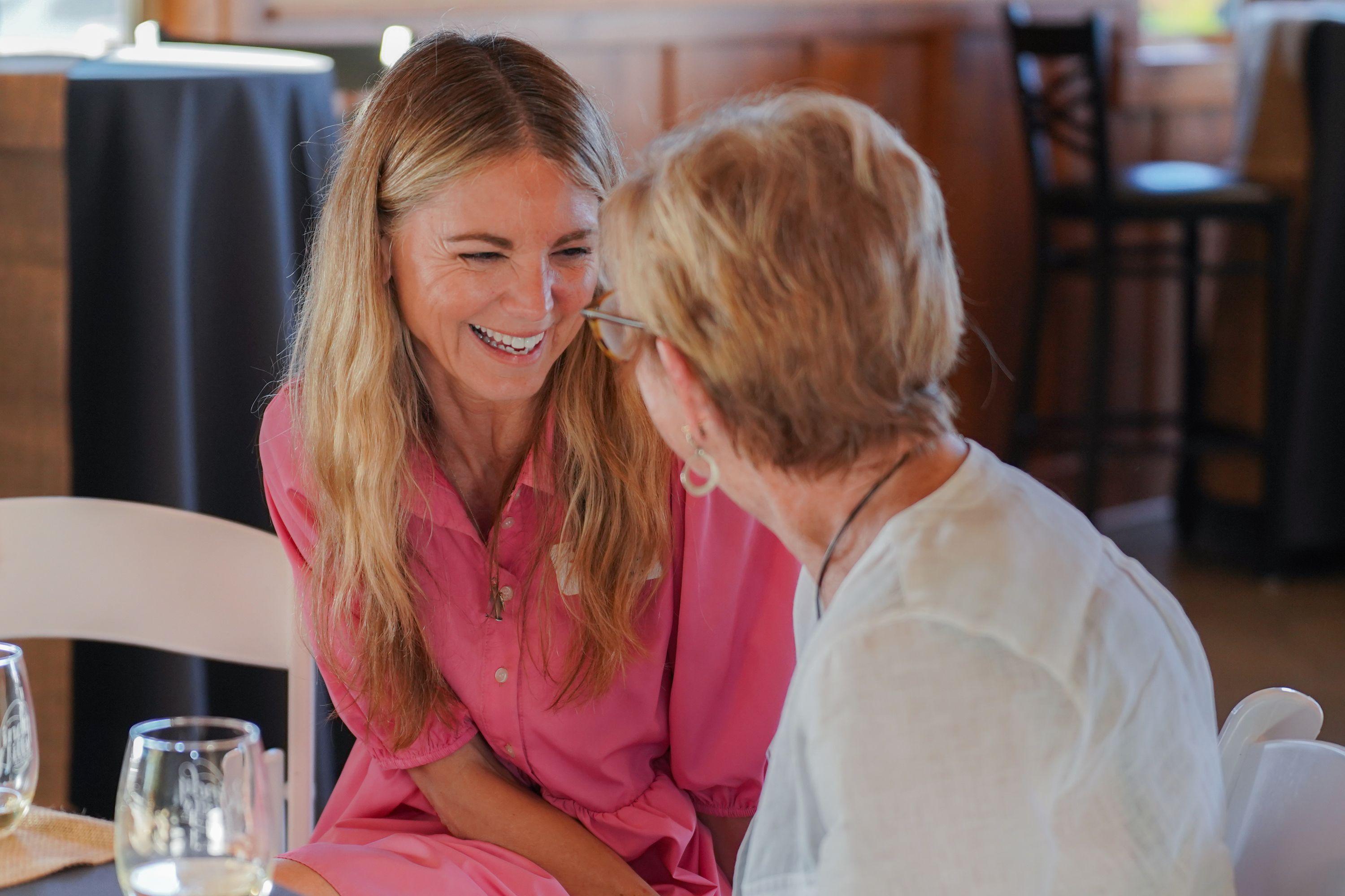 Development Coordinator Chrissy Brown laughing and talking with a donor at a table