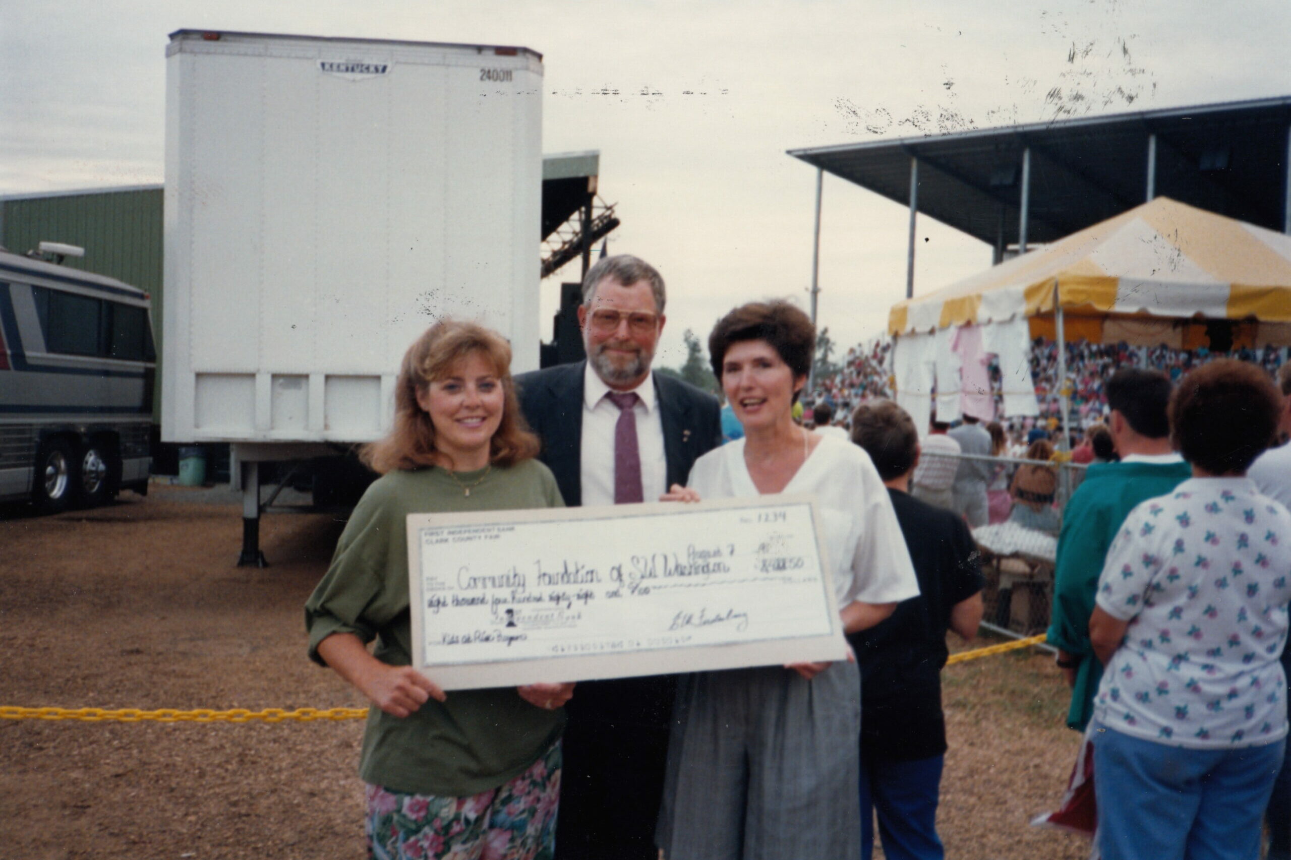 A large check being presented with a smile.